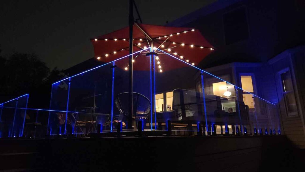 Glass deck railing with blue accent lighting at night