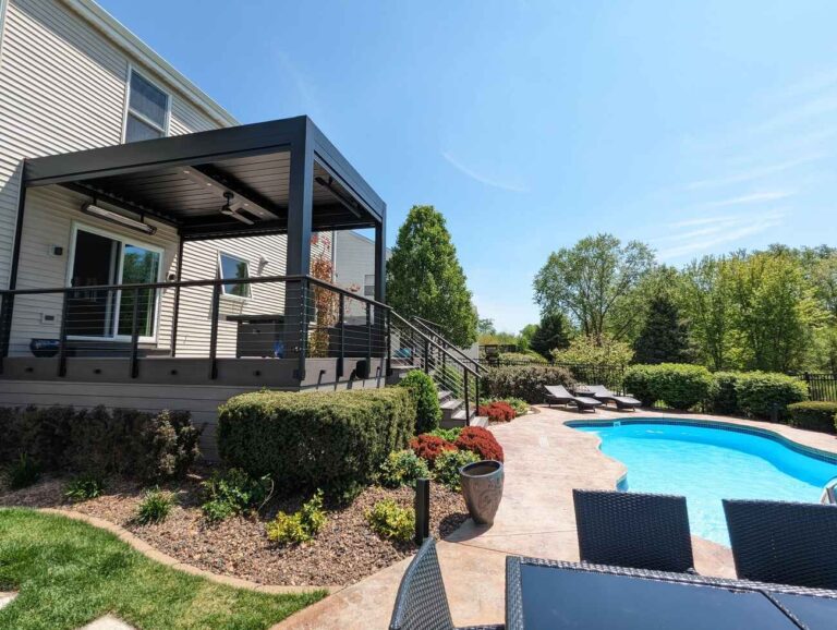 The finished louvered pergola and deck stairs leading to the pool patio