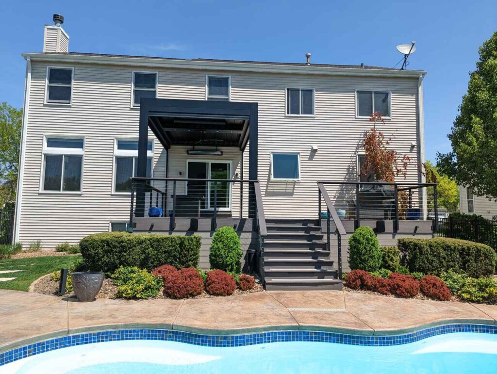 Two-story home with a new deck, pergola and wide stairs down to the pool