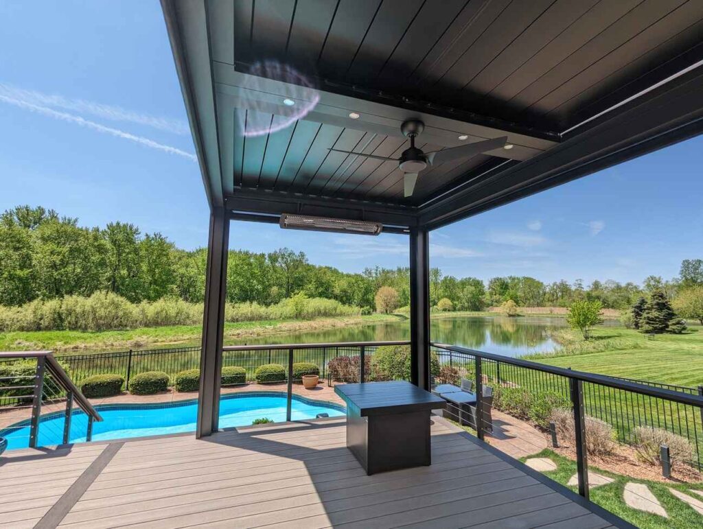 View from under a louvered pergola across the pool to a pond