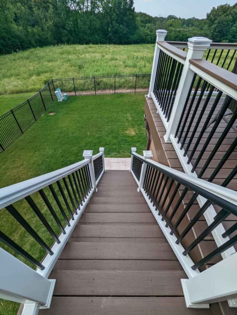 Deck stairs with white railing down to the yard
