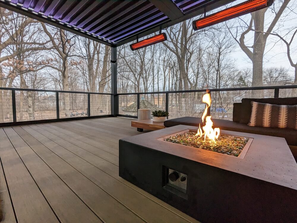 Fire table burning under a louvered roof with infrared heaters