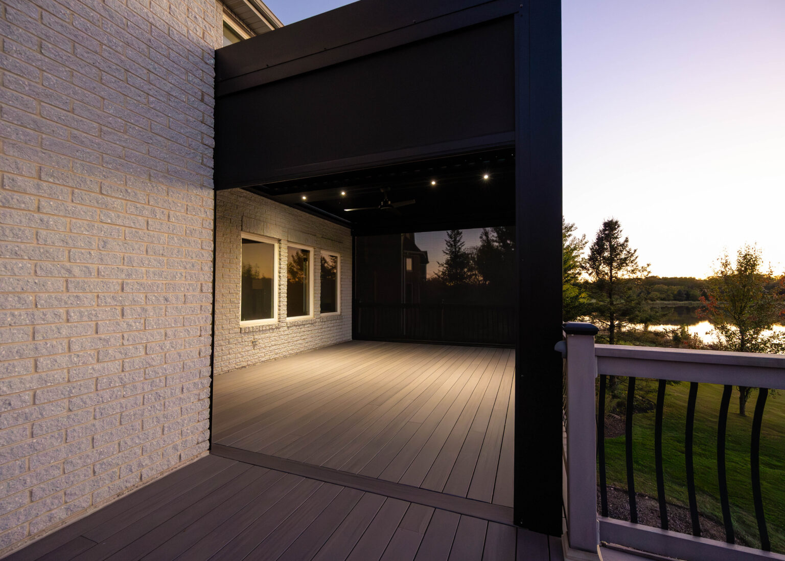 Louvered pergola roof and deck at dusk beside the house
