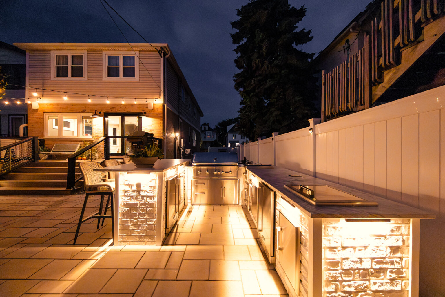 Outdoor kitchen with lit counters and bar seating at night