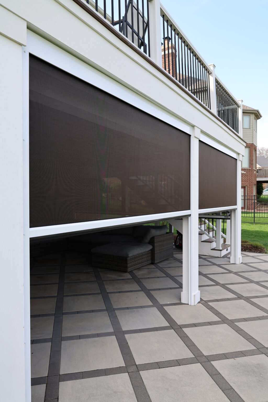 Motorized screen lowered under a deck between white posts