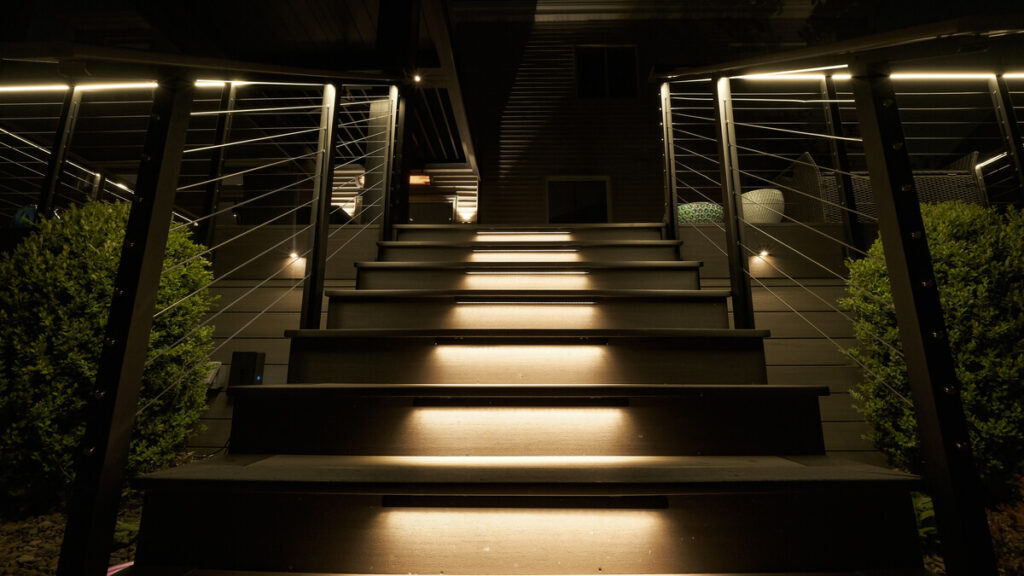 Lit stair treads between cable railings at night