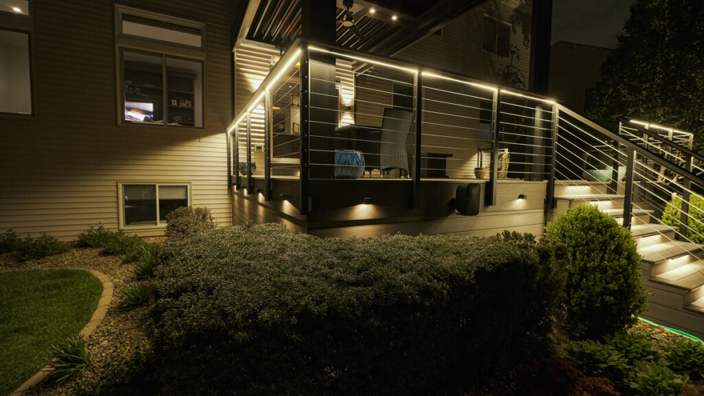 Deck rail lighting glowing above the landscaping at night