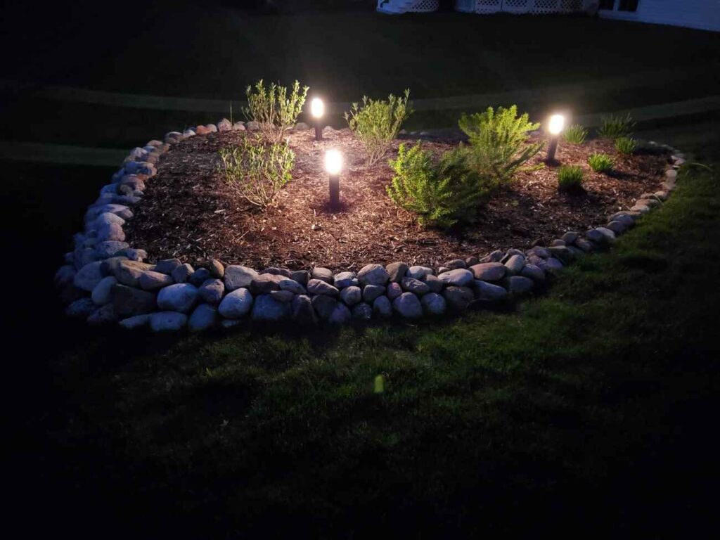 Path lights in a stone-edged garden bed at night