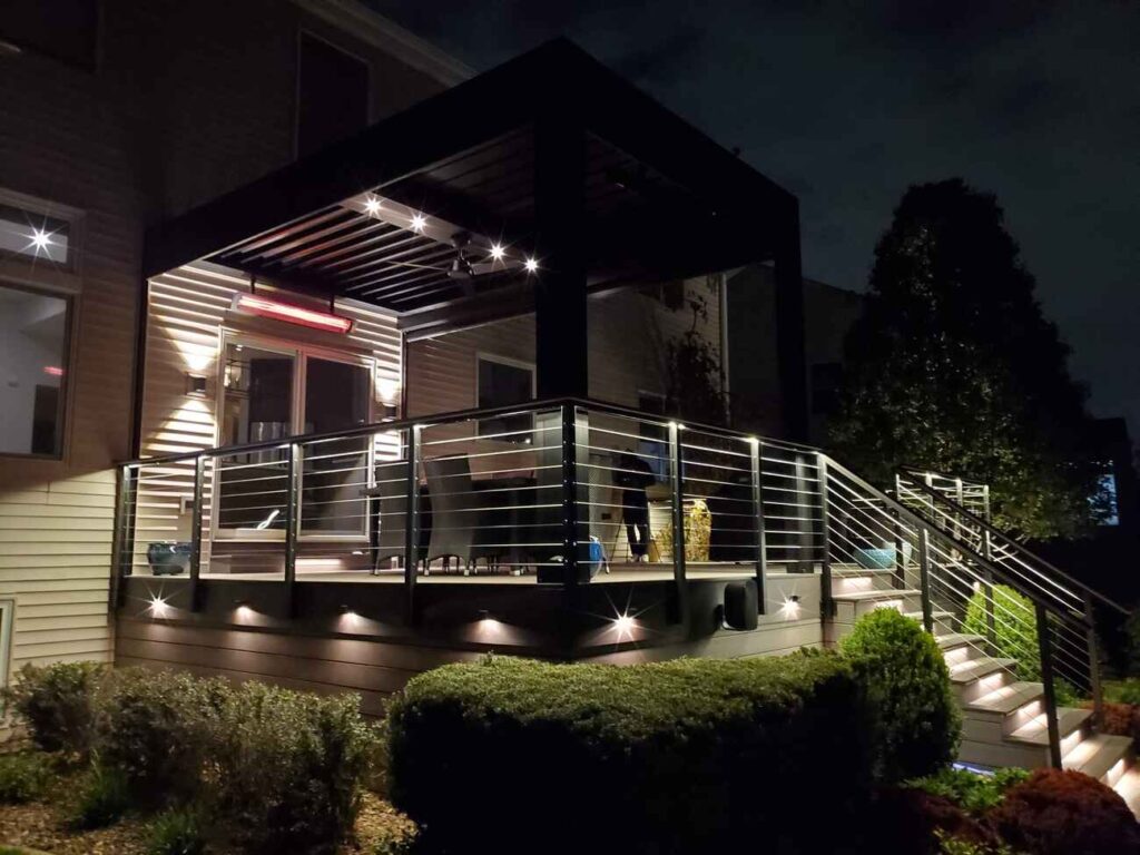 Deck and louvered pergola lit at night with rail and step lighting