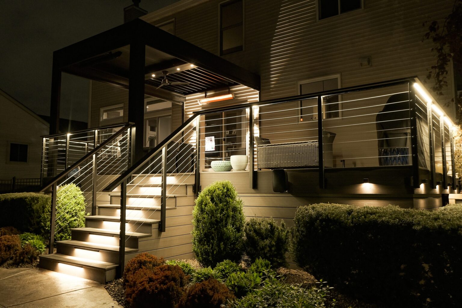 Completed Ace of Decks build at night: composite deck with illuminated stair treads and cable railing